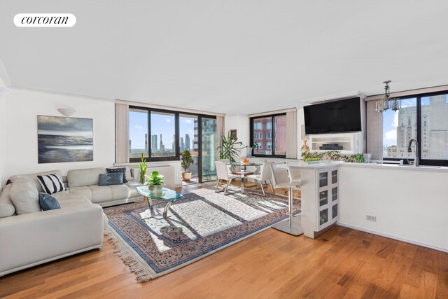 living room featuring expansive windows, sink, light hardwood / wood-style flooring, and a notable chandelier