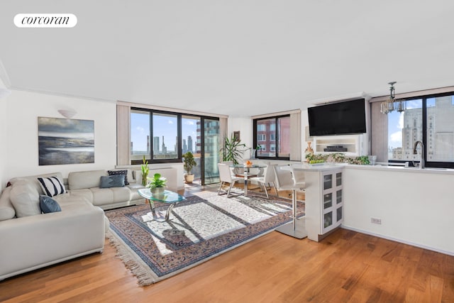 living room featuring a wealth of natural light, visible vents, a notable chandelier, and wood finished floors