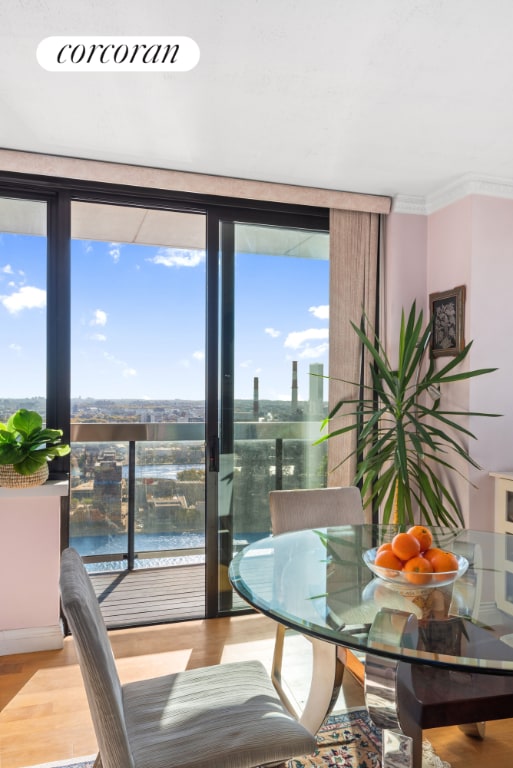 dining space with a water view, ornamental molding, a healthy amount of sunlight, and hardwood / wood-style flooring