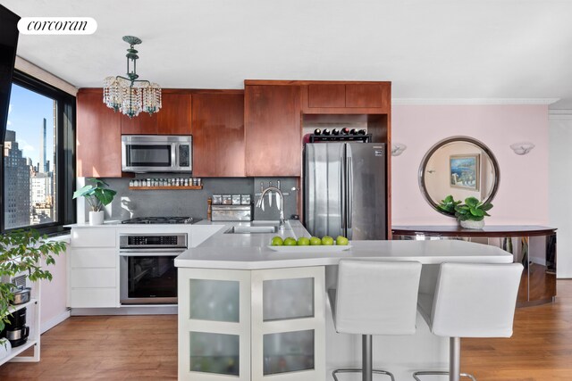 kitchen with sink, hanging light fixtures, stainless steel appliances, white cabinets, and decorative backsplash