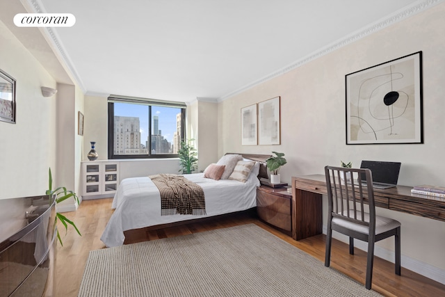 bedroom with a view of city, ornamental molding, and light wood-type flooring