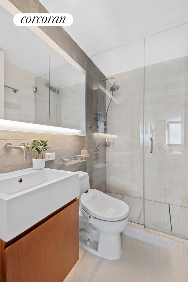 bathroom with tile walls, vanity, tasteful backsplash, a shower with shower door, and toilet