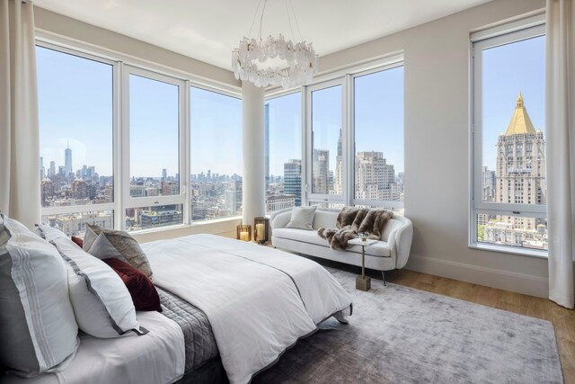 bedroom featuring multiple windows, a city view, and wood finished floors