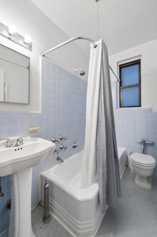 full bathroom with sink, tile walls, shower / tub combo, tile patterned floors, and toilet