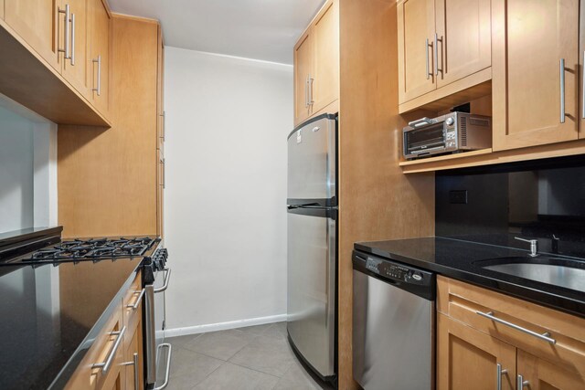 kitchen with light tile patterned floors, dark stone counters, and stainless steel appliances