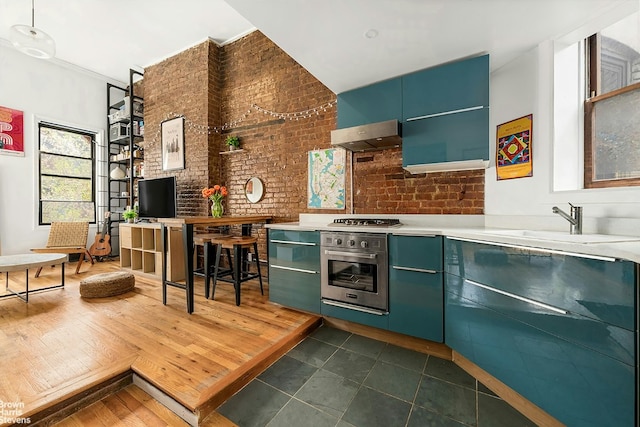 kitchen with sink, appliances with stainless steel finishes, extractor fan, and brick wall