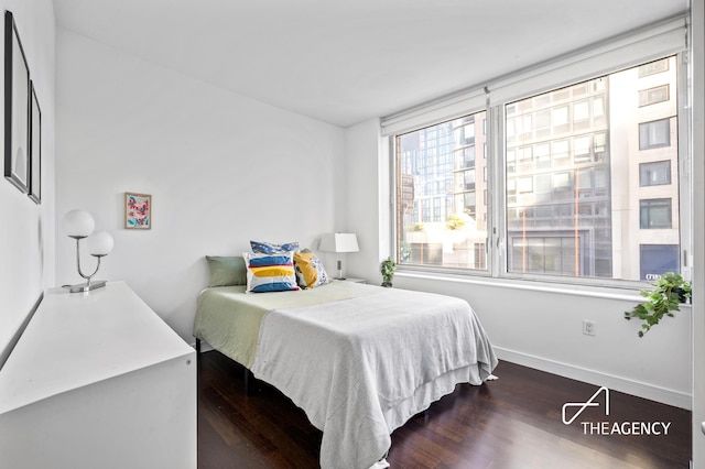 bedroom with dark wood-type flooring and baseboards