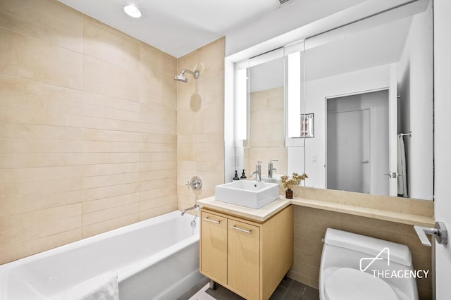 bathroom with tile walls, shower / bath combination, vanity, and toilet