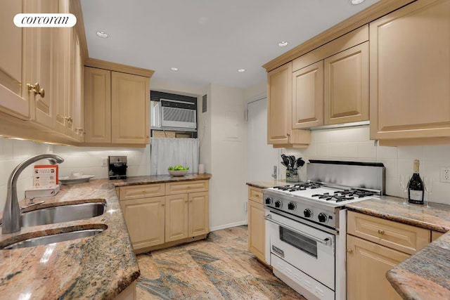 kitchen featuring white range with gas stovetop, decorative backsplash, light stone countertops, an AC wall unit, and a sink