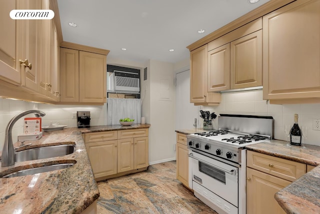 kitchen with light stone countertops, a sink, gas range gas stove, stone finish flooring, and backsplash