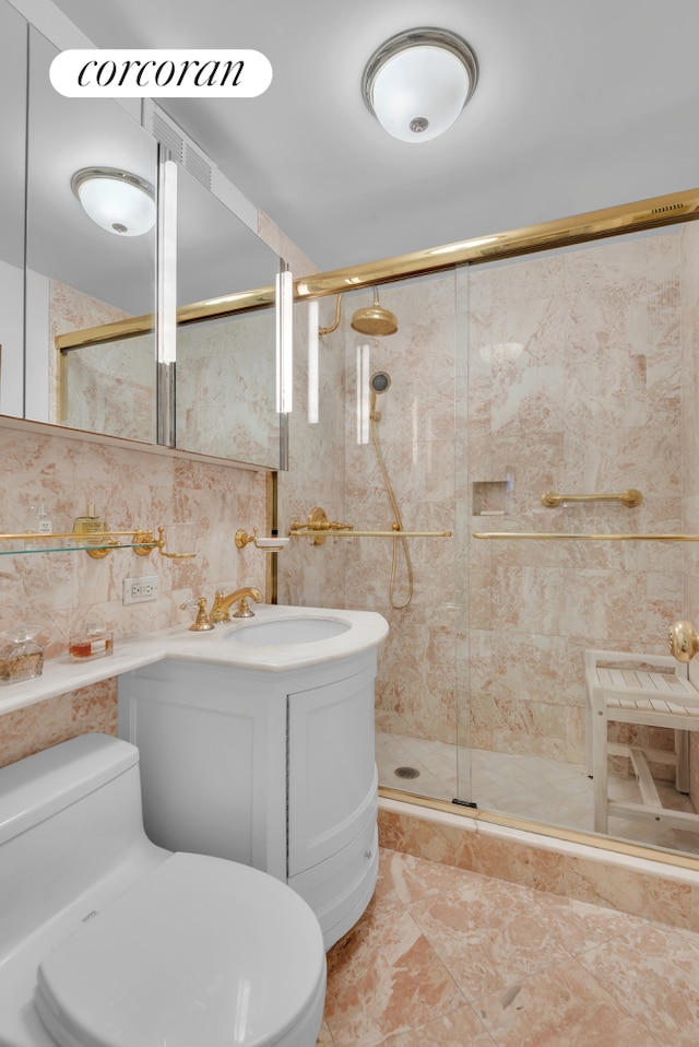 bathroom with vanity, tile walls, toilet, and a shower stall