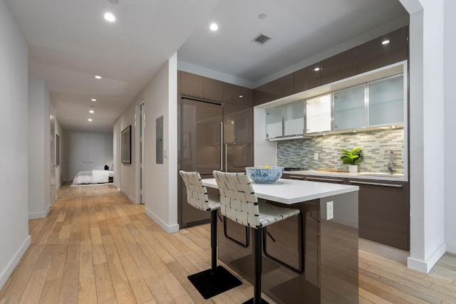 kitchen featuring a kitchen bar, light hardwood / wood-style flooring, dishwasher, a kitchen island, and backsplash