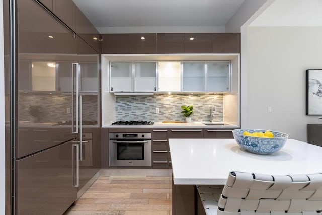 kitchen with sink, decorative backsplash, stainless steel appliances, and light hardwood / wood-style floors