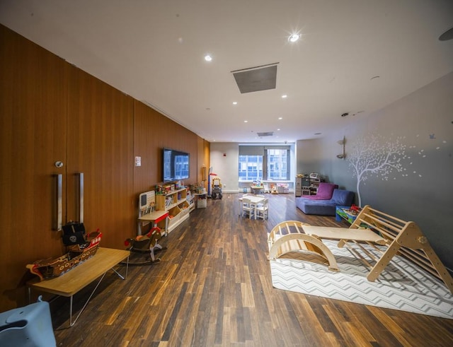 living room with recessed lighting, wood finished floors, and wood walls