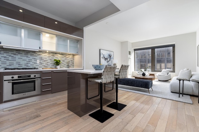 75 Wall St Unit 26A, New York City, NY 10005 - kitchen featuring oven, a breakfast bar, modern cabinets, light countertops, and open floor plan