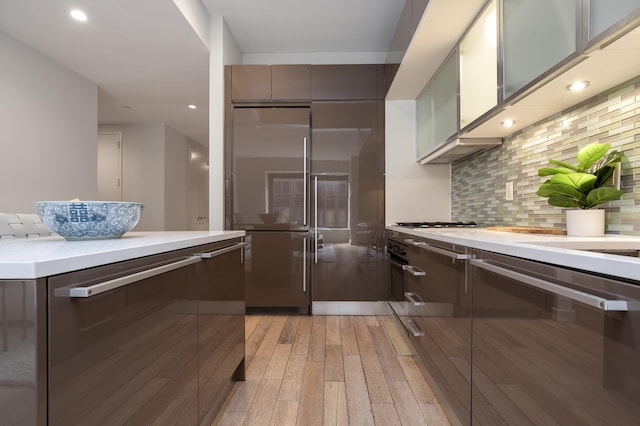75 Wall St Unit 26A, New York City, NY 10005 - kitchen with high quality fridge, light wood-style flooring, light countertops, decorative backsplash, and modern cabinets