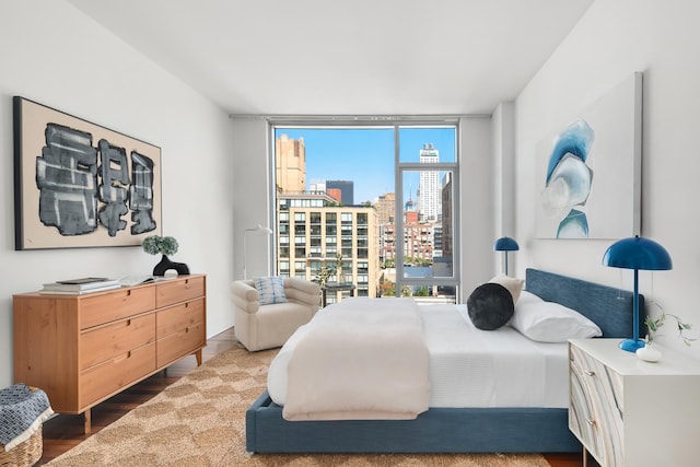 bedroom with a city view, wood finished floors, and expansive windows