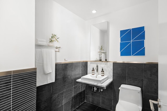 bathroom featuring recessed lighting, a sink, wainscoting, tile walls, and toilet