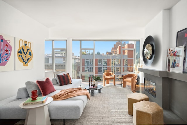 interior space with a glass covered fireplace, a wall of windows, a city view, and wood finished floors