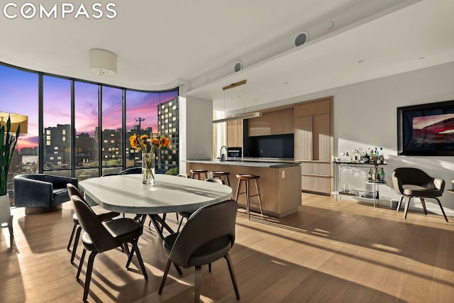 dining space featuring sink, a wall of windows, and light wood-type flooring