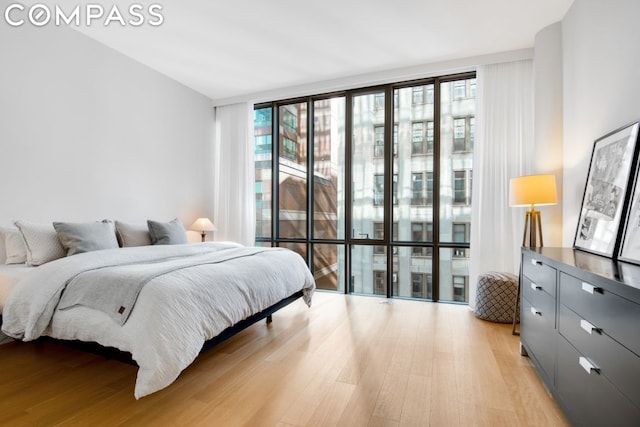 bedroom with expansive windows, light wood-type flooring, and multiple windows