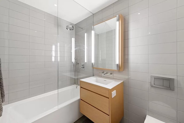 full bathroom featuring tiled shower / bath combo, tile walls, and vanity