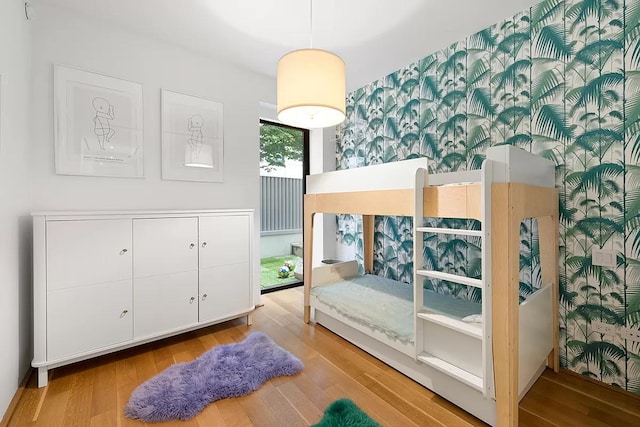 bedroom featuring wood finished floors and wallpapered walls