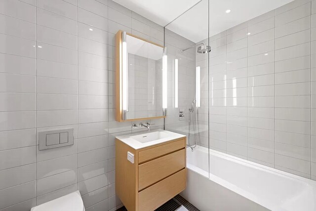 full bath featuring shower / bathing tub combination, tile walls, toilet, and vanity