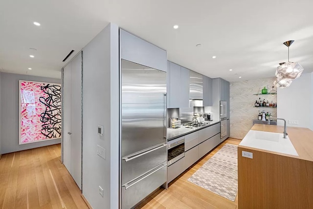 kitchen featuring light wood-style floors, a sink, modern cabinets, and stainless steel gas stovetop