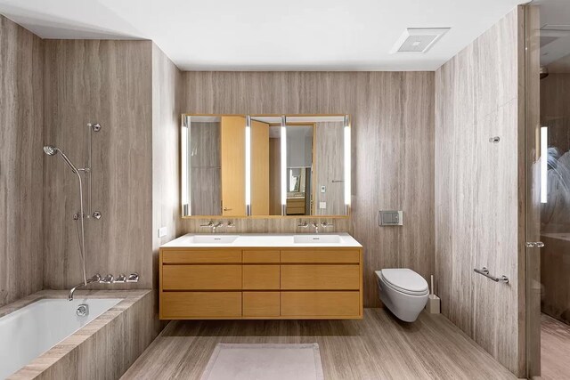 full bath with wood finished floors, a sink, double vanity, and toilet