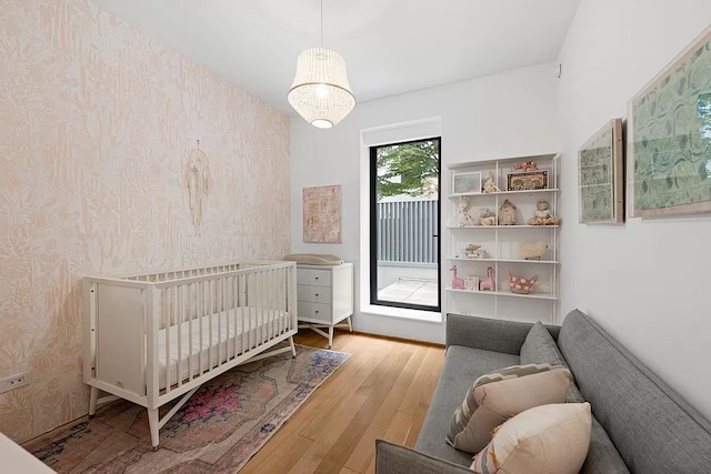 bedroom with wallpapered walls, wood finished floors, and access to exterior