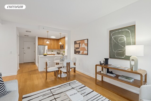 living area featuring light wood-type flooring, visible vents, and baseboards