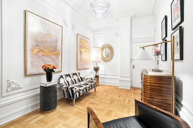 living area featuring light parquet flooring, ornamental molding, and a notable chandelier