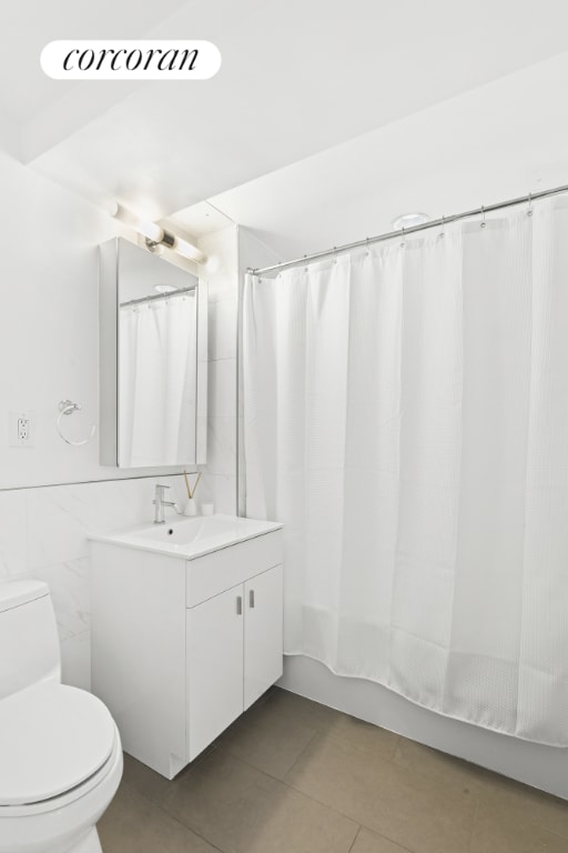 full bathroom with toilet, vanity, tile walls, tile patterned flooring, and shower / tub combo