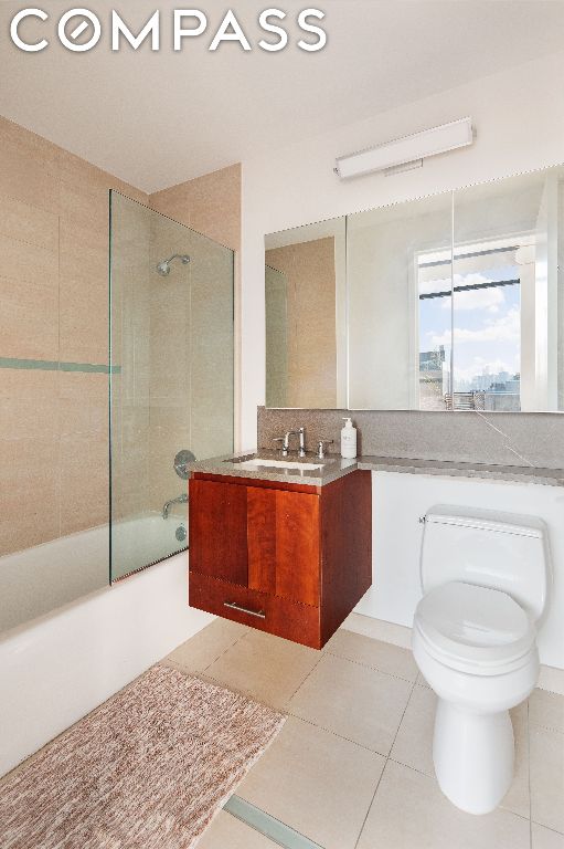 full bathroom featuring vanity, bath / shower combo with glass door, tile patterned floors, and toilet