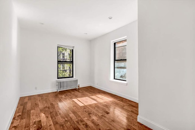 empty room with hardwood / wood-style flooring and radiator heating unit