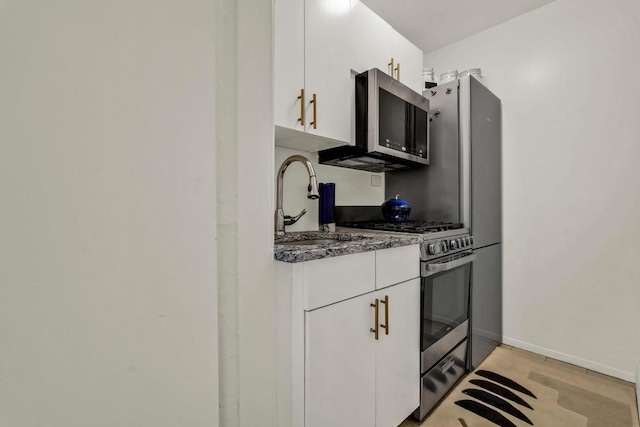 kitchen with dark stone countertops, sink, white cabinets, and appliances with stainless steel finishes