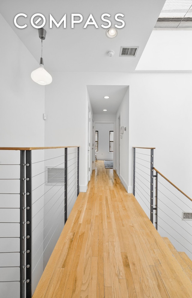 corridor with recessed lighting, visible vents, an upstairs landing, wood finished floors, and baseboards