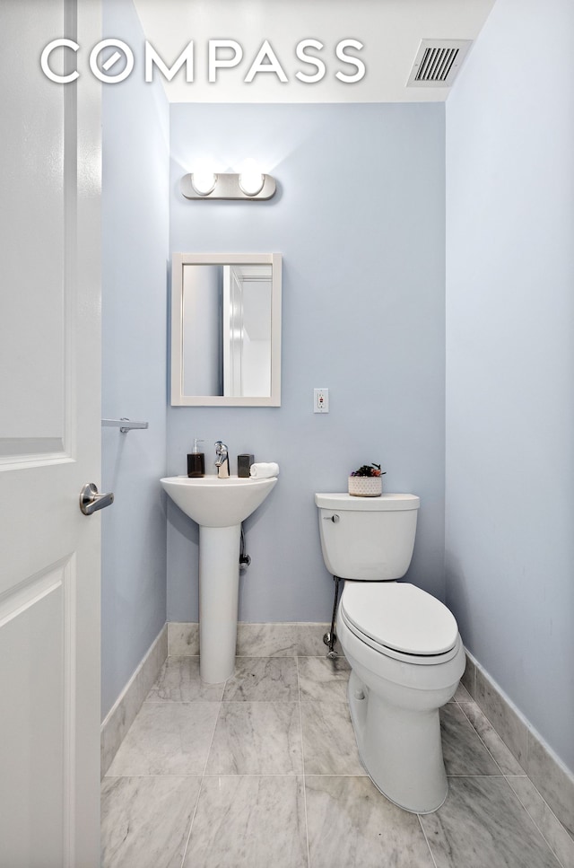 half bathroom with toilet, baseboards, and visible vents