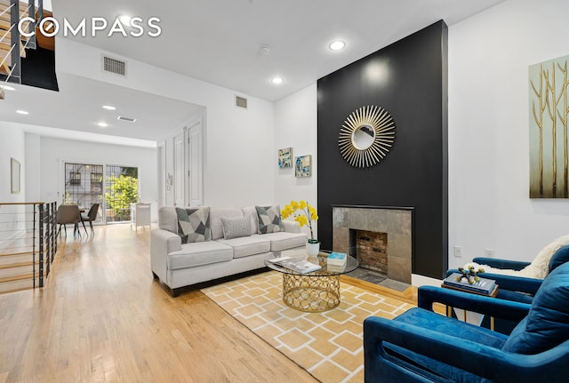 living area with visible vents, a tile fireplace, and wood finished floors