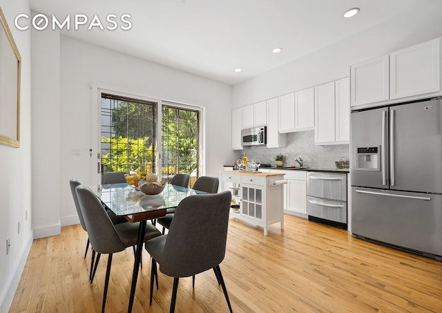 dining space featuring light wood-style floors, recessed lighting, and baseboards