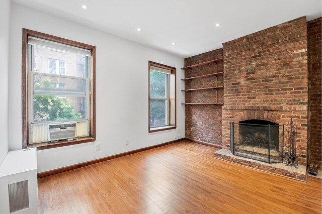146 W 82nd St Unit 3A, New York City, NY 10024 - unfurnished living room with wood finished floors, baseboards, cooling unit, a brick fireplace, and recessed lighting