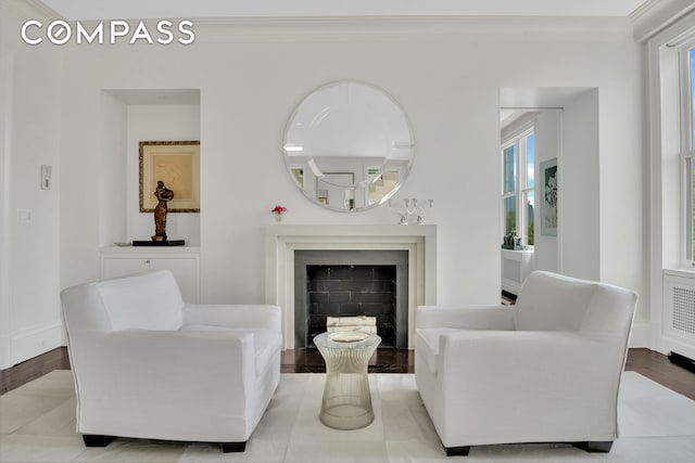 living room with baseboards, wood finished floors, ornamental molding, and a fireplace