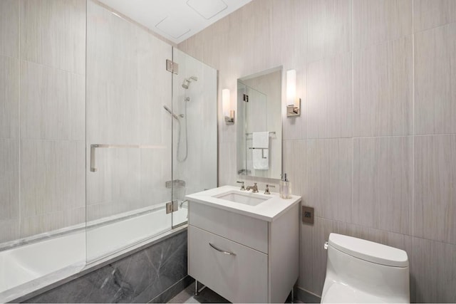 full bathroom with toilet, tile walls, vanity, and tiled shower / bath combo