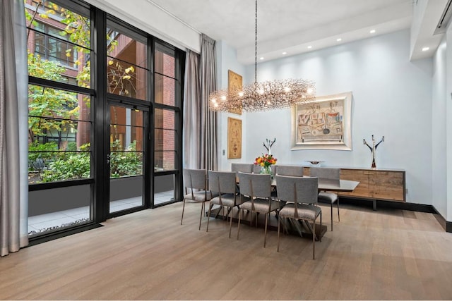 dining space with a wealth of natural light, light hardwood / wood-style floors, a high ceiling, and a chandelier