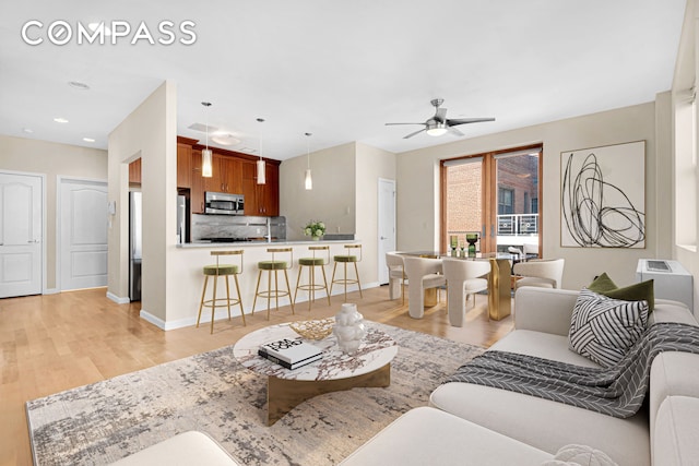 living area featuring recessed lighting, baseboards, light wood-style flooring, and a ceiling fan