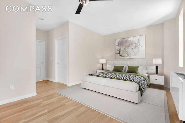 bedroom featuring baseboards, light wood-style floors, and a ceiling fan