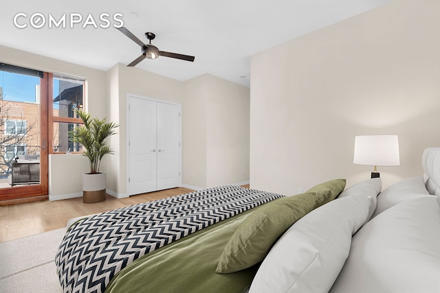 bedroom with a closet, a ceiling fan, light wood-type flooring, and baseboards