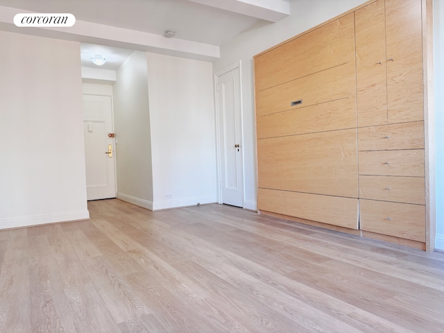 spare room with light wood-type flooring, visible vents, and baseboards