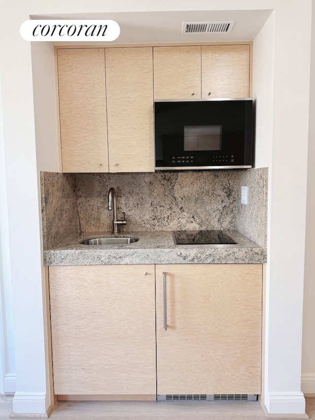 kitchen with visible vents, light countertops, cream cabinetry, a sink, and black appliances